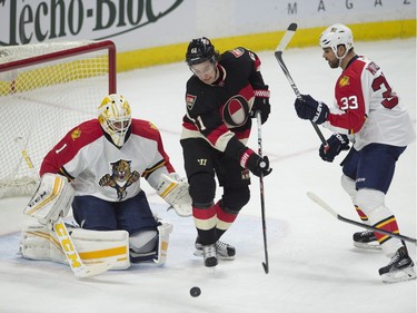 Ottawa Senators right wing Mark Stone takes a swing at a bouncing puck in front of Florida Panthers goalie Roberto Luongo and defenseman Willie Mitchell during first period NHL action.