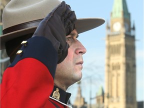 With Parliament Hill in the background, a Mountie salutes.