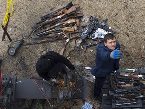 This 2014 file photo shows workers as they cut weapons in half during the destruction of firearms held illegaly in Kosovo. The process is part of efforts to increase security in the Balkan country.