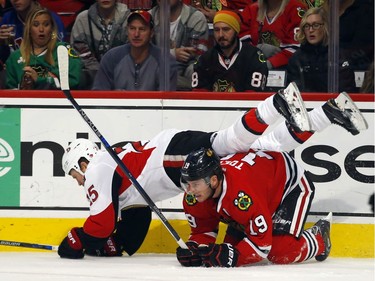 Ottawa Senators center Zack Smith (15) falls over Chicago Blackhawks center Jonathan Toews (19) during the first period of an NHL hockey game Sunday, Jan. 3, 2016, in Chicago.