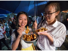 Zoe Feng (L) and Nisha Lou taste the so-called "Smelly Tofu" as the first ever Ottawa Night Market hosted by the Ottawa Asian Festival which kicked off at Lansdowne Park in Ottawa. )