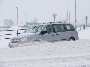 A car drives through a furrow left by a plow on Walkley Road at Bank Street as the region deals with a major snow storm.