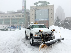 A truck plows snow in front of Ottawa City Hall.