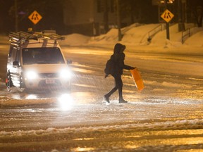 A pedestrian crosses a sloppy looking Greenbank Rd as the region deals with another snow storm followed by freezing rain.