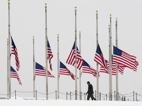 A pedestrian walks past flags flying at half-staff in Washington. D.C. this week to mark the passing of U.S. Supreme Court Justice Antonin Scalia.