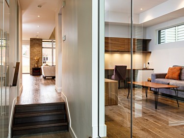 A hallway leads from the foyer to the main living area. Like much of the house, it has engineered hickory barn wood flooring. On the right is the den; the glass brings light from the foyer into the room. Just visible to the left are the handles of a custom closet.