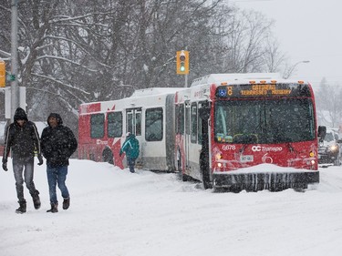 An articulated bus blocks afternoon commuters on Alta Vista Drive after it got stuck in the snow as the region deals with a major snow storm.