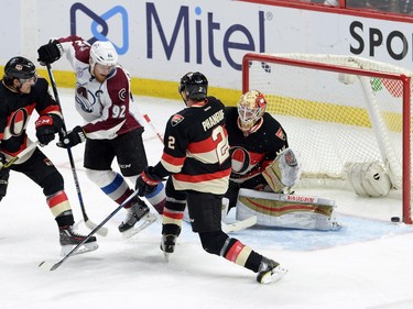 Ottawa Senators' Cody Ceci (5) and Dion Phaneuf (2) defend against Colorado Avalanche's Gabriel Landeskog (92) as a shot goes off the goal post beside Senators goalie Andrew Hammond during first period NHL action.