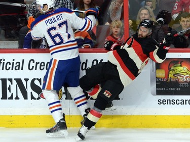 Edmonton Oilers' Benoit Pouliot pushes Ottawa Senators' Erik Karlsson to the ice during first period NHL action.