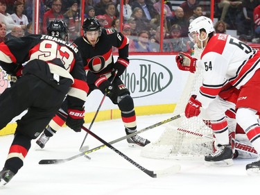 Bobby Ryan, middle, and Mika Zibanejad of the Ottawa Senators cycle the puck against #54 Brett Pesce of the Carolina Hurricanes during first period NHL action.