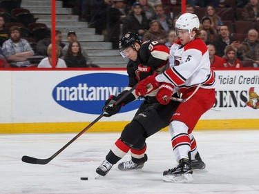 Alex Chiasson #90 of the Ottawa Senators drives to the net as he is held up by Noah Hanifin #5 of the Carolina Hurricanes.