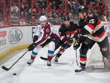 Chris Bigras #3 of the Colorado Avalanche protects the puck behind the net as Curtis Lazar #27 and Chris Neil #25 to the Ottawa Senators pressure on the forecheck.