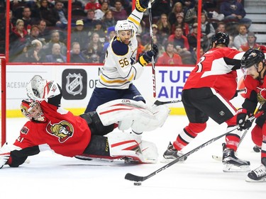 Craig Anderson, left, of the Ottawa Senators tries to save the puck as it is cleared by Erik Karlsson, right, as Josh Bailey of the Buffalo Sabres looks on during second period NHL action.