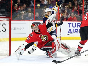 Craig Anderson of the Ottawa Senators tries to save the puck as as Josh Bailey of the Buffalo Sabres looks on during second period NHL action.