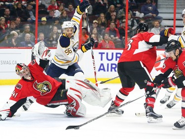 Craig Anderson of the Ottawa Senators tries to save the puck as it is cleared by Erik Karlssonas Josh Bailey of the Buffalo Sabres looks on during second period NHL action.