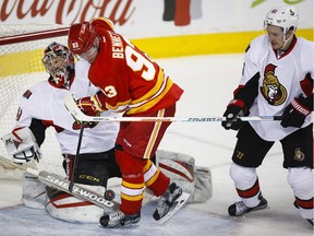 The Flames' Sam Bennett collides with Ottawa Senators goalie Craig Anderson as Mark Stone looks on during the first period in Calgary on Saturday, Feb. 27, 2016.