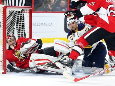 Craig Anderson of the Ottawa Senators follows the puck as he is tackled to the ground by Brian Gionta of the Buffalo Sabres during second period NHL action.