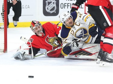 Craig Anderson of the Ottawa Senators follows the puck as he is tackled to the ground by Brian Gionta of the Buffalo Sabres during second period NHL action.