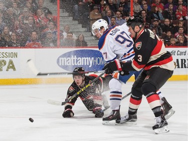 Connor McDavid #97 of the Edmonton Oilers dekes Jean-Gabriel Pageau #44 and Marc Methot #3 of the Ottawa Senators for a scoring chance.