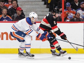 Bobby Ryan #6 of the Ottawa Senators chips the puck past Mark Fayne #5 of the Edmonton Oilers.