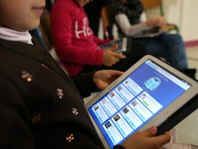 Schoolchildren use digital tablets in a classroom.