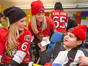 (from left) Danielle Ryan, wife of Bobby Ryan and Nicholle Anderson, wife of Craig Anderson get a smile out of Karim Chabi, 14, after they gave him a toque as Ottawa Senators wives and girlfriends make a visit to the Children's Hospital of Eastern Ontario to meet with a few patients to lift their spirits in advance of Valentine's Day.