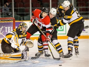 Kingston goalie Jeremy Helvig keeps his eyes on the puck while 67's player Connor Warnholtz is held back by Ted Nichol and Conor McGlynn in the first period.