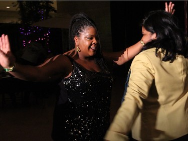 From left, Suzan Lavertu from The School of Afro-Caribbean Dance, gets Jamaican High Commissioner Janice Miller on the dance floor at On the Rocks: In the Caribbean, an annual Winterlude party hosted by the Ottawa Art Gallery at City Hall on Friday, February 5, 2016. (Caroline Phillips / Ottawa Citizen)