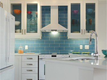 Glenview Homes’ award-winning Adirondack model home showcases a fun kitchen where the white chimney hood fan pops against an electric blue tile backsplash.