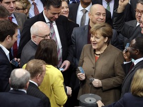 German Chancellor Angela Merkel holds her ballot card as she talks to lawmakers during an asylum debate of the German Bundestag in Berlin on Feb. 25.