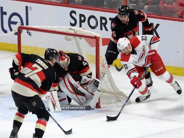Carolina Hurricanes' Kris Versteeg attempts a wrap around goal on Ottawa Senators' Craig Anderson as Kyle Turris, left, and Cody Ceci defend during first period NHL action.