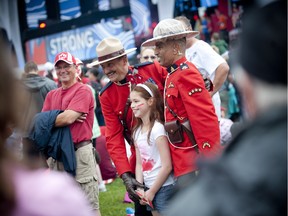 Two Mounties pose with a girl for a photo during the 2015 Canada Day noon show on Parliament Hill.