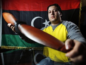 Mohamed Khlell, an airline transport pilot student from Libya, displays a replica antique prop and Libyan flag at his rental house in Ottawa.