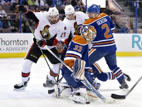 Ottawa Senators ' Nick Paul (13) and Curtis Lazar (27) battle with Edmonton Oilers' Andrej Sekera (2) as goalie Cam Talbot (33) makes the save during first period NHL action.