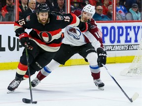 Ottawa Senators center Zack Smith (15) fights off the check of Colorado Avalanche left wing Blake Comeau (14).