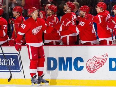 Danny DeKeyser #65 of the Detroit Red Wings pounds gloves with teammates on the bench after his goal during the first period.
