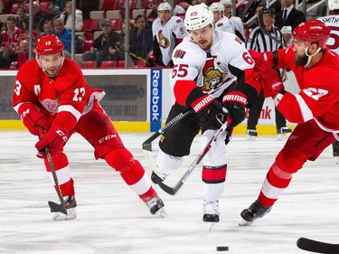 Erik Karlsson #65 of the Ottawa Senators battles for the puck with Kyle Quincey #27 and Pavel Datsyuk #13 of the Detroit Red Wings.