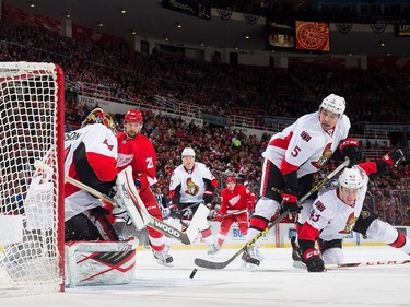 Craig Anderson #41 of the Ottawa Senators makes a save as teammates Cody Ceci #5 and Ryan Dzingel #43 follow the puck.