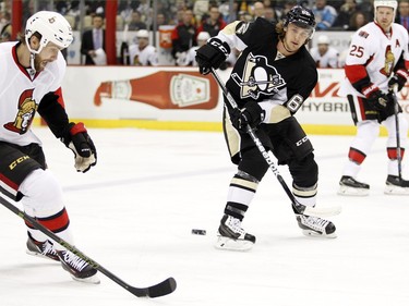 Carl Hagelin #62 of the Pittsburgh Penguins makes a pass against Zack Smith #15 of the Ottawa Senators.