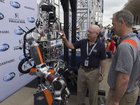 150606-N-PO203-311 POMONA, California (June 6, 2015) Dr. Tom McKenna, left, a program officer at the Office of Naval Research (ONR), talks with Dr. Brian Latimer, associate professor at Virginia Tech, about ESCHER, short for Electric Series Compliant Humanoid for Emergency Response, during the Defense Advanced Research Projects Agency Robotics Challenge (DRC) in Pomona, Calif. Designed, fabricated and assembled by engineering students at Virginia Tech, ESCHER leverages software and design learnings from another project underway at the lab, the ONR-sponsored Shipboard Autonomous Firefighting Robot, or SAFFIR. (U.S. Navy photo by John F. Williams/Released)