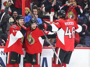 Ryan Dzingel, left, celebrates his first goal with Chris Wideman, and Patrick Wiercioch, right, during first period NHL action.