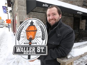 George Bush, a salesman with the Waller St. Brewing Co., poses with a replacement sign created and donated by rival brewer,  Broadhead Brewing Co, after the original was stolen.