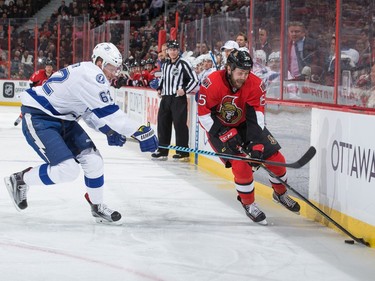Zack Smith #15 of the Ottawa Senators stickhandles the puck along the boards as Andrej Sustr #62 of the Tampa Bay Lightning defends.