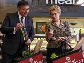 Premier Kathleen Wynne and Finance Minister Charles Sousa pose with bottles of Ontario wine at a Toronto Longo's grocery store.