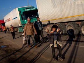 KILIS, TURKEY - FEBRUARY 09: A young boy living at the Kilis refugee camp carries supplies along the road at the closed Turkish border gate on February 9, 2016 in Kilis, Turkey. According to Turkish officials some 35,000 Syrian refugees have massed on the Syrian/Turkish border after fleeing Russian airstrikes and a regime offensive surrounding the city of Aleppo in northern Syria. Turkey's President Recep Tayyip Erdogan said Turkey would open it's doors" if necessary".