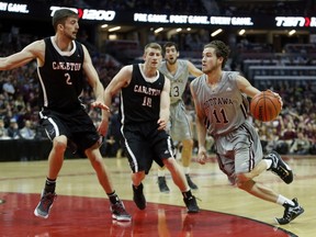 The Gee-Gees' Mike L'Africain drives on the Ravens' Cameron Smythe, left, and Connor Wood.