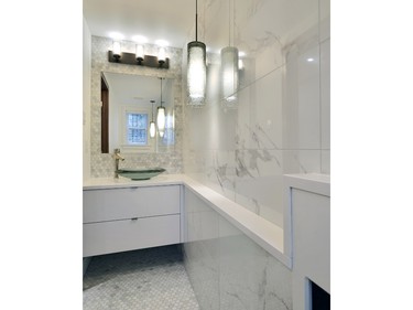 A long and narrow space called for a creative approach by Amsted Design-Build in this powder room entry at last year's Housing Design Awards. Large white marble tiles on the main wall play down the length, while a decorative grate cover that hides a radiator is blended into the room by a ledge built out from the wall and clad in the same white stone as the counter for an elegant and serene look.