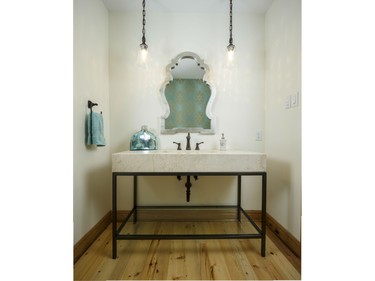 An open vanity from Restoration Hardware set on reclaimed pine floors keeps this powder room airy while bringing together the idea of modern and country. Add in the wallpaper and mirror for a touch of nostalgia. The project by Cornelis Grey Construction was a finalist in the 2015 Housing Design Awards in the new category of powder room.