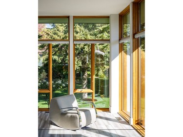 The large windows help integrate the interior and exterior, while discreet roller blinds provide privacy when needed in the sitting room of the mid-century-inspired Massey House by Art House Developments. The painted drywall between the stained pine frames gives the windows a clean, defined look. 'If we’d clad them just in pine, they would have looked too heavy and cottagey,' says Art House president Alex Diaz.