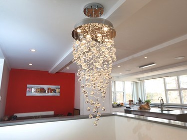 A large contemporary chandelier from Arevco Lighting hangs over the open stairwell, which twists down to the half-basement level.